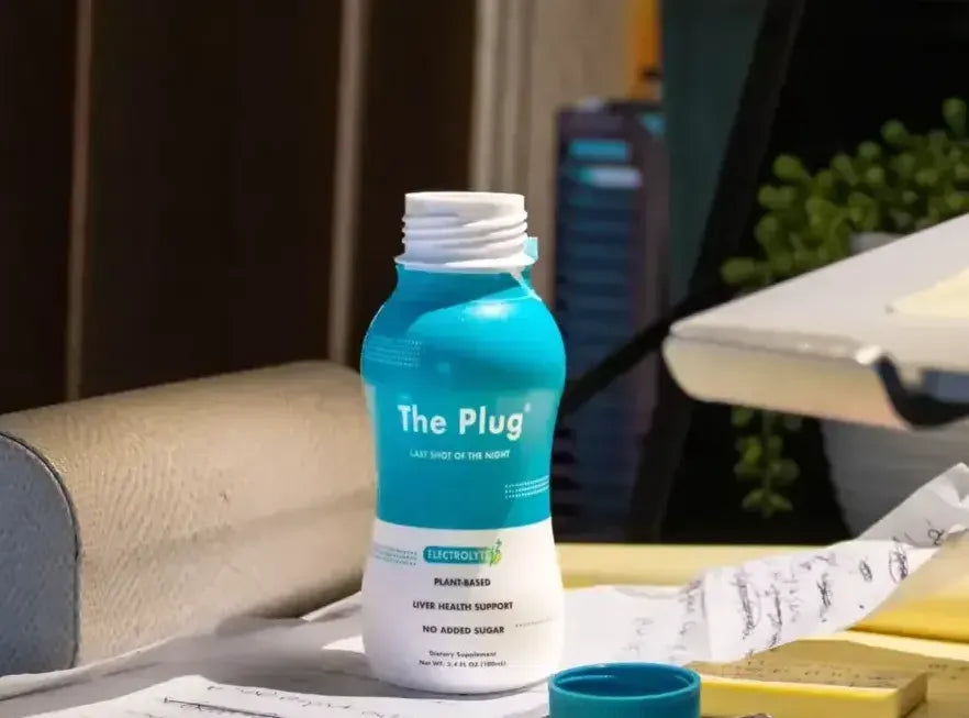 A bottle of The Plug Drink on a desk beside handwritten notes