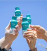 Friends toasting with bottles of The Plug hangover drink against a blue sky