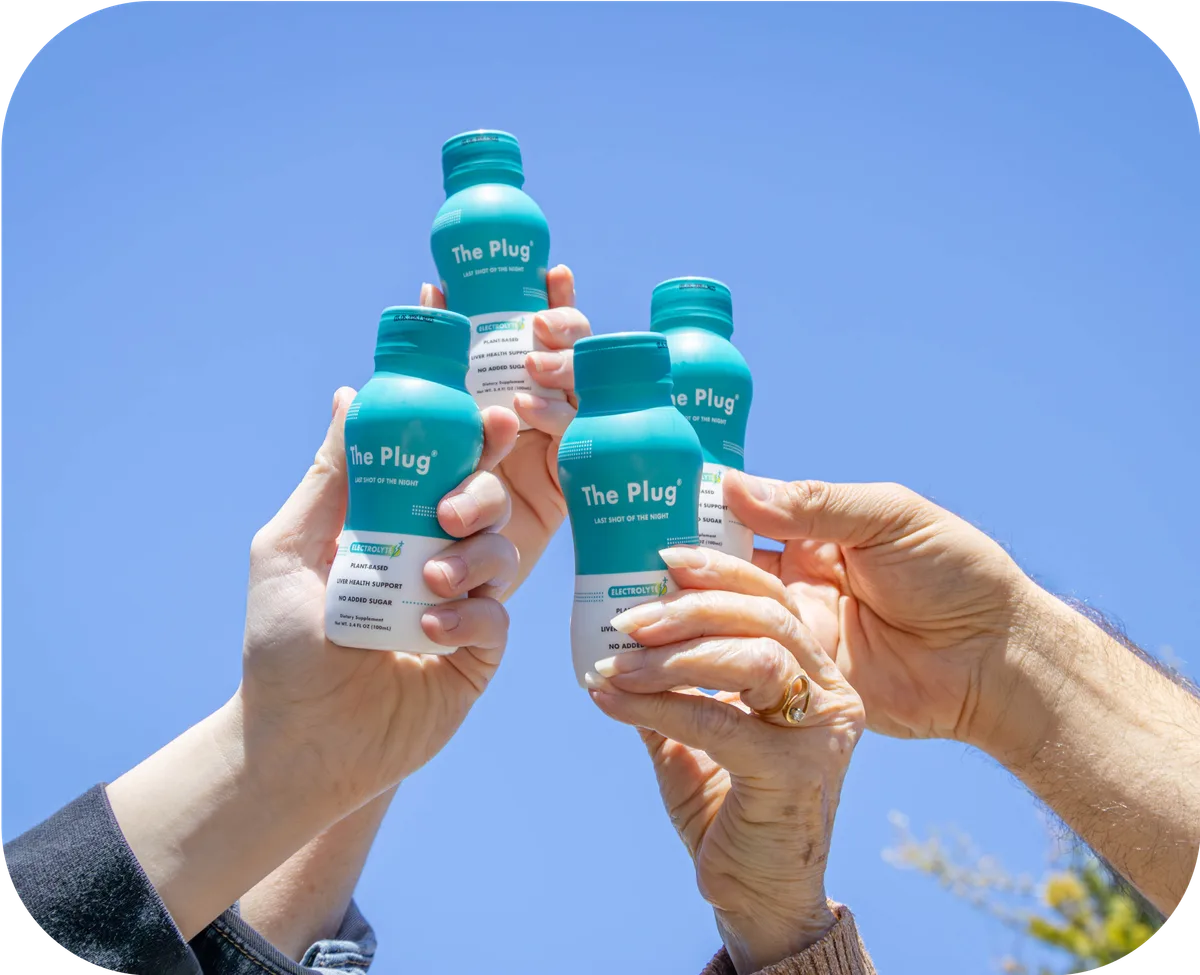Friends toasting with bottles of The Plug hangover drink against a blue sky