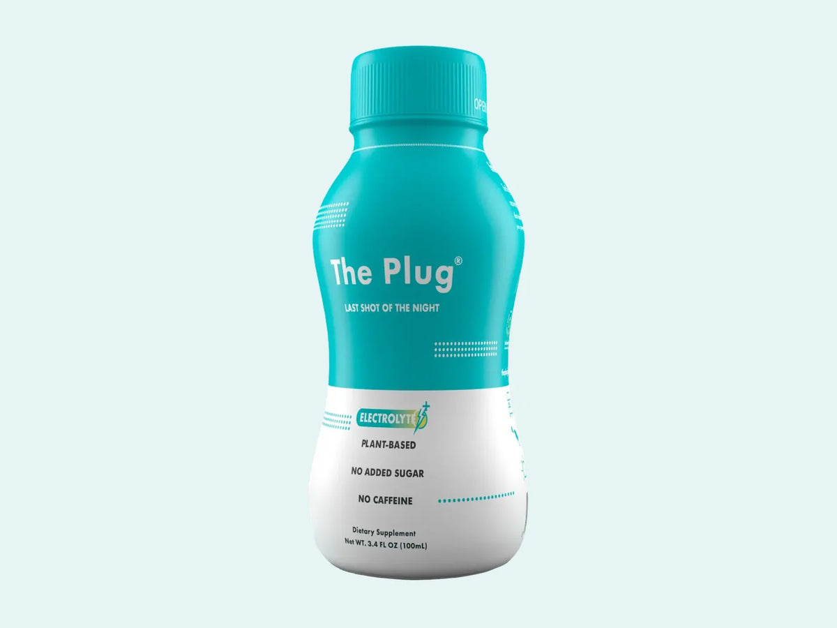 A bottle of The Plug Drink stands against a pale teal background.