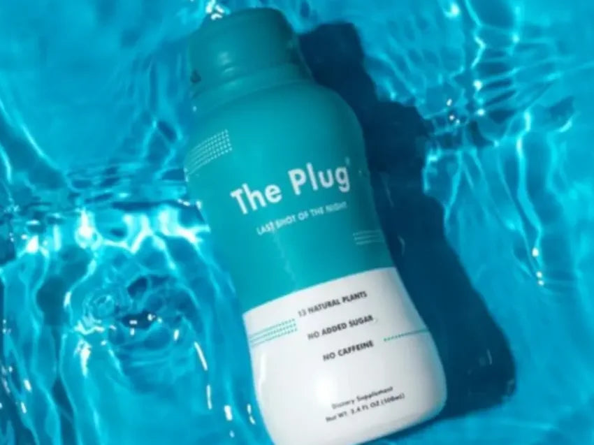 A bottle of The Plug Drink floats in bright blue pool water.