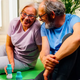 Older couple smiling together on a yoga mat with The Plug liver support drink bottles beside them
