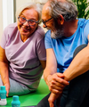 Older couple smiling together on a yoga mat with The Plug liver support drink bottles beside them