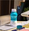 Open bottle of The Plug liver health drink on a desk with notes and a pen
