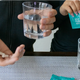 Person holding Milk Thistle Turmeric Vitamin B liver support capsules alongside a glass of water
