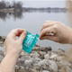 Person opening a Milk Thistle Turmeric Vitamin B liver support packet outdoors by a lake