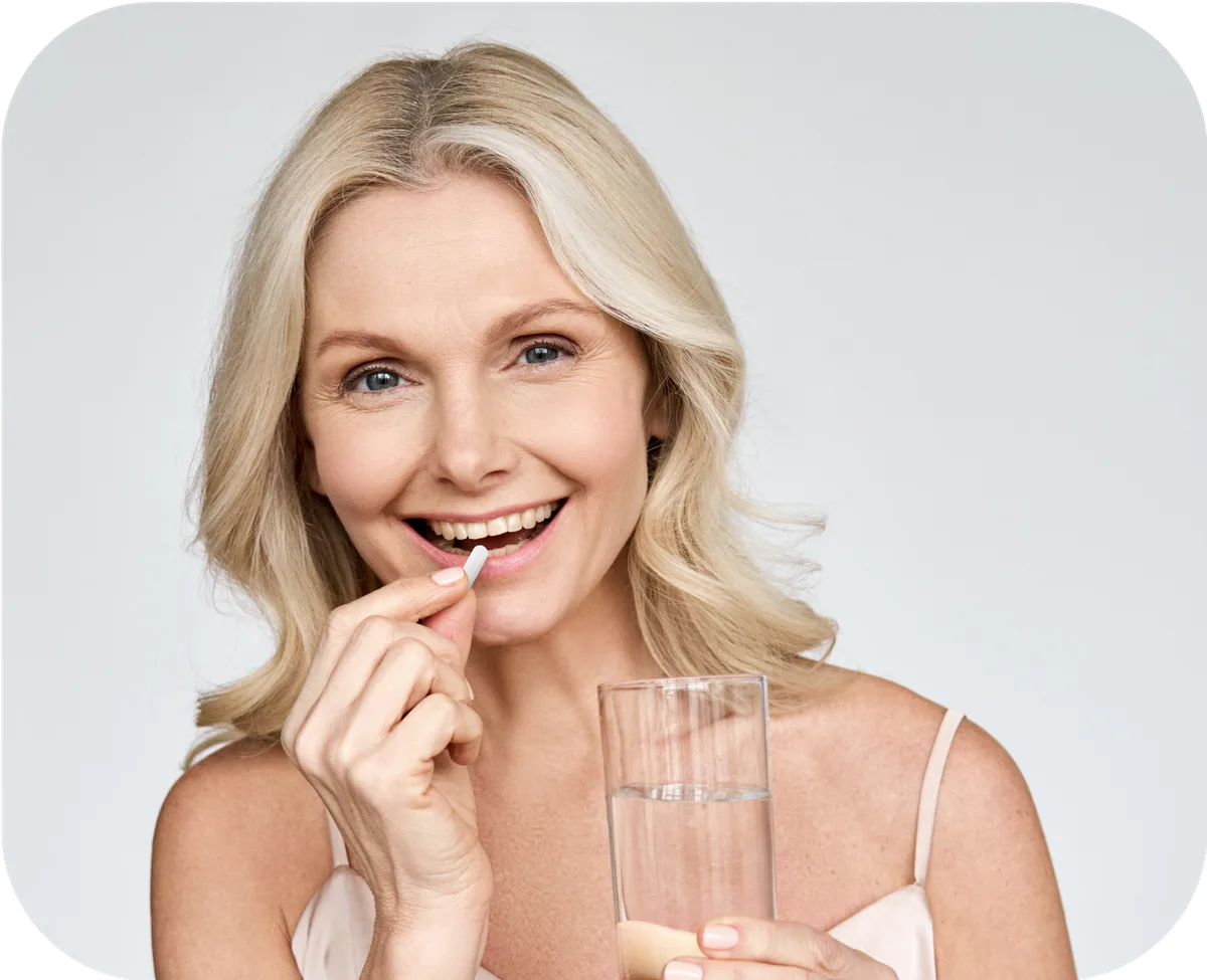 Smiling woman taking a Milk Thistle liver support capsule with a glass of water