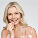 Smiling woman taking a Milk Thistle liver support capsule with a glass of water