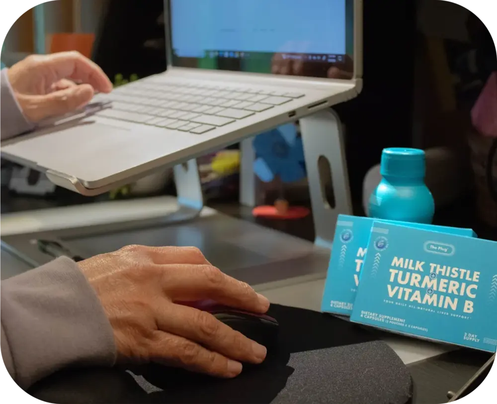 The Plug liver health drink bottle beside a laptop on a desk
