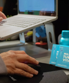 The Plug liver support drink bottle and Milk Thistle Turmeric Vitamin B pill boxes on a desk next to a laptop