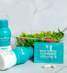 The Plug liver support drink bottle, Milk Thistle Turmeric Vitamin B pills, and a fresh salad