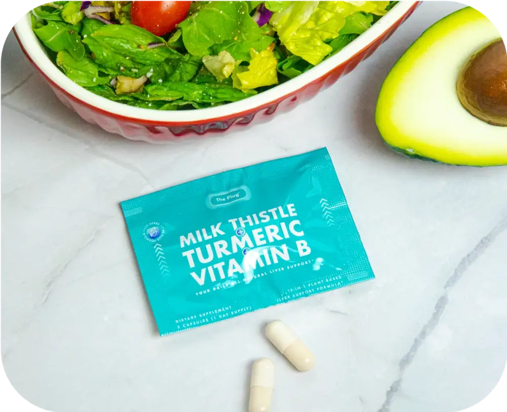The Plug Milk Thistle Turmeric Vitamin B liver support packet and capsules next to a salad and avocado
