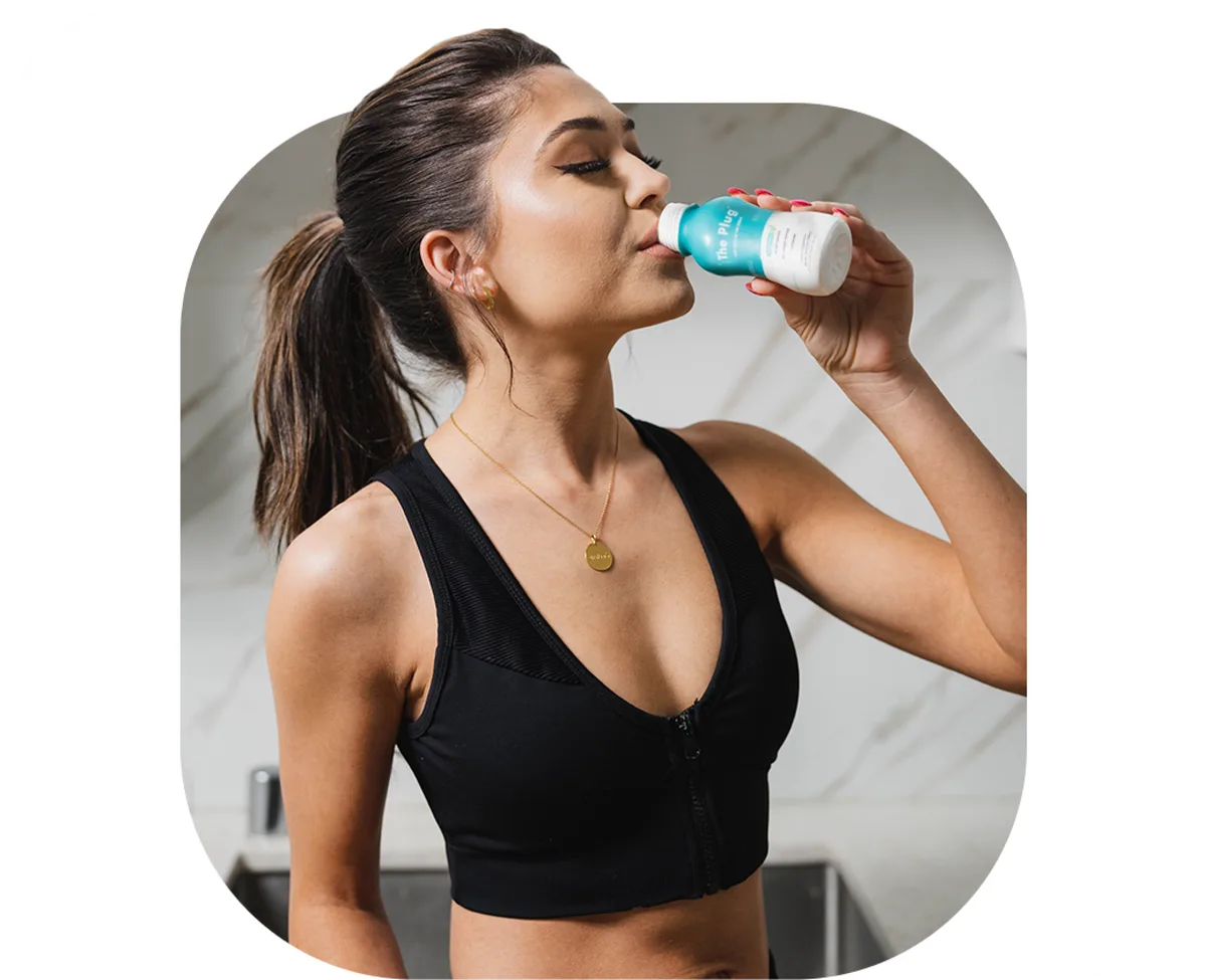 Woman in workout gear drinking The Plug hangover drink after exercising