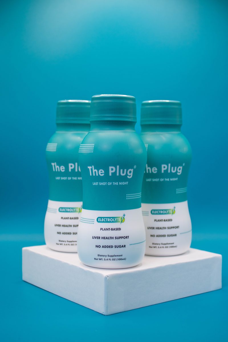 Three bottles of The Plug Drink in a teal studio