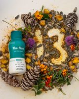 A bottle of The Plug Drink inside a 13 made of plants and flowers