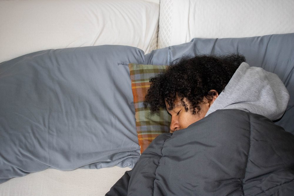 A person asleep under a grey duvet