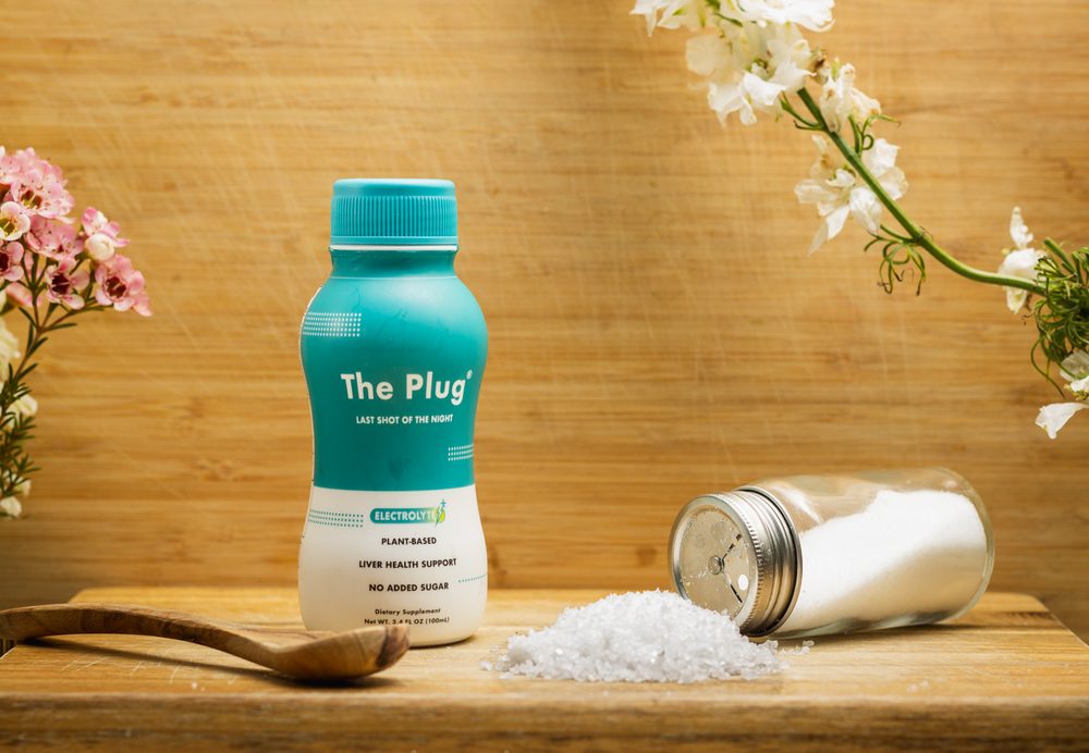 A bottle of The Plug Drink beside a spoon of spilled salt